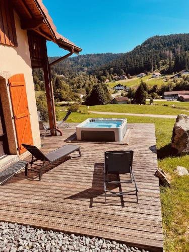 a wooden deck with two chairs and a pool at La Gouleote Spacieuse maison type chalet avec jacuzzi, sauna, pétanque in Gérardmer