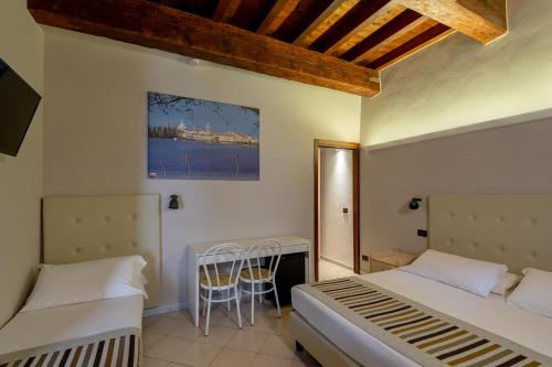 a bedroom with two beds and a table in it at Abbazia Bed & Breakfast, MantegnaHotels in Mantova