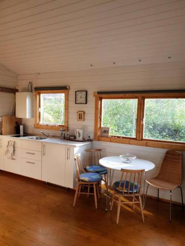 cocina con mesa y sillas y 2 ventanas en Cozy cottage in the south, en Keldur