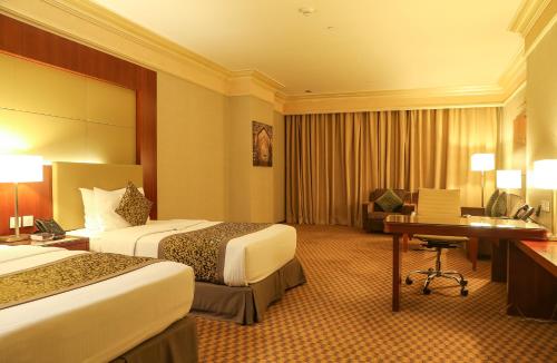 a hotel room with two beds and a desk at Wyndham Garden Dammam in Dammam