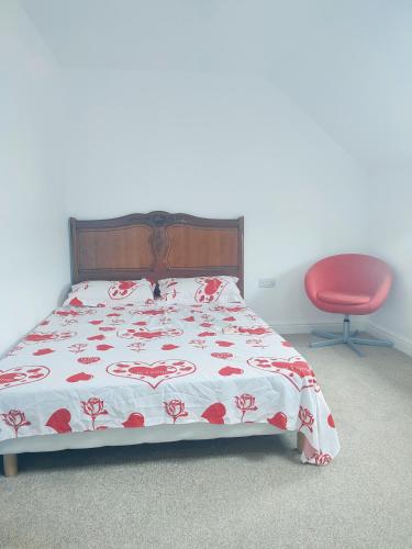 a bedroom with a bed and a red chair at Madif Ensuite in Leicester