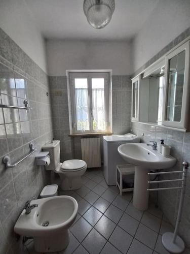 a white bathroom with two sinks and a toilet and a sink at La casa dei nonni in Lucca