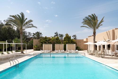 uma piscina com cadeiras e guarda-sóis num resort em Almazino, Almaza Bay em Mājid Abū Zayd