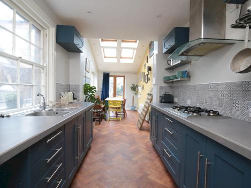 uma grande cozinha com armários azuis e um lavatório em Pass the Keys Charming Victorian Townhouse Central Oxford em Oxford