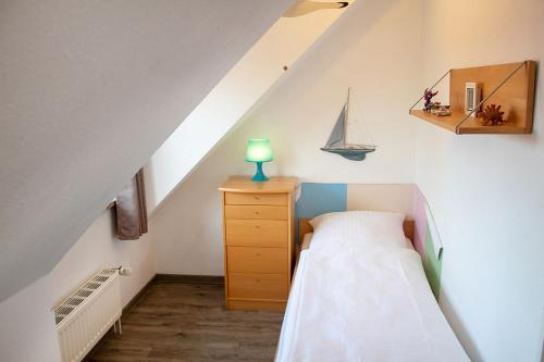 um pequeno quarto no sótão com uma cama e um veleiro na parede em ST4-12 - Ferienwohnung Komfort em Dorum Neufeld