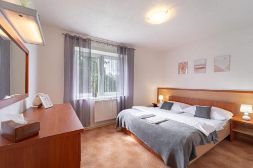 a bedroom with a bed and a desk and a window at Penzión Živa Bijacovce in Bijacovce