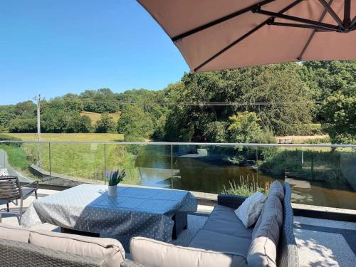 a patio with a couch and a table with a view of a river at Riverside Retreat in Llandysul