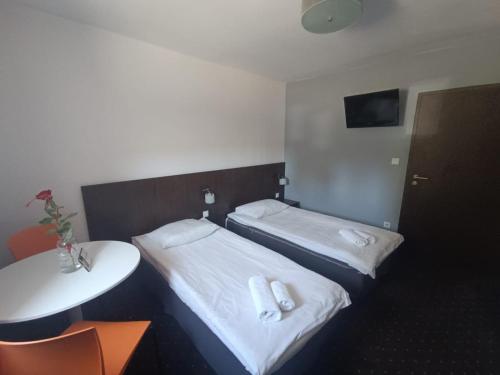 a room with two beds and a table and a sink at Aparthotel Strefa Budget in Tychy