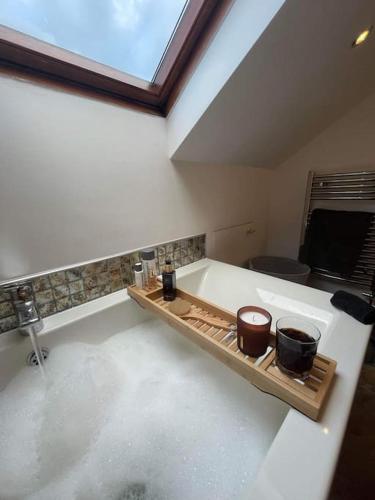 a bathroom with a bath tub with two pots on a shelf at Riverside Retreat in Llandysul