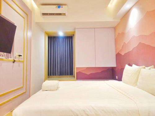a bedroom with a large white bed with a window at Pinky Rose @Anderson Apartment in Surabaya