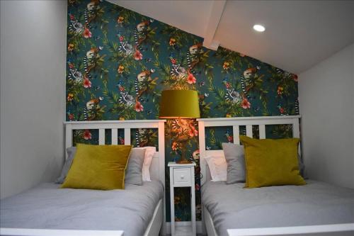 2 camas en un dormitorio con papel pintado floral en Luxury 2-Bed Cottage in Llansteffan, en Carmarthen