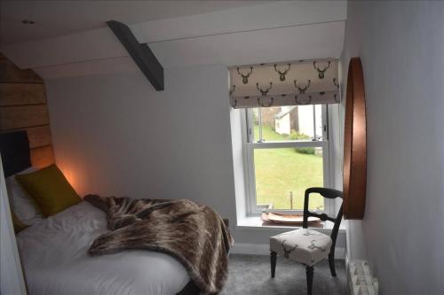 a bedroom with a bed and a window and a chair at Llansteffan 2-Bed Cottage Sleeps 4 Dog Ok in Carmarthen