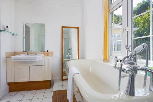 a white bathroom with a tub and a sink at Cliff Cottage in Brixham