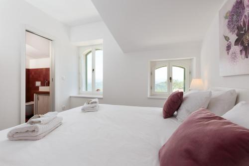 a white bedroom with a large white bed and windows at Casa Histria in Motovun