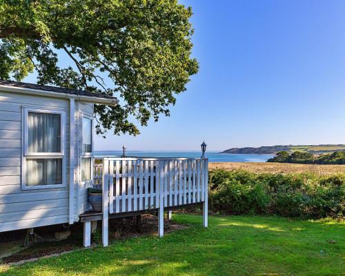 a blue house with a white fence and the ocean at Finest Retreats - Ocean View in Porchfield