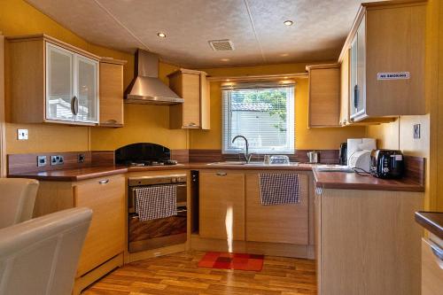 a kitchen with wooden cabinets and a sink at Finest Retreats - Ocean View in Porchfield