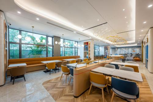 a restaurant with tables and chairs and windows at Holiday Inn Express Jiangmen East Station, an IHG Hotel in Jiangmen