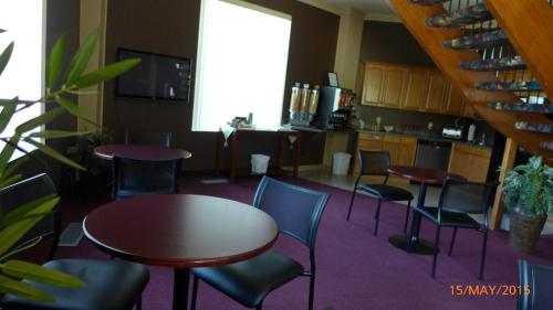 a room with tables and chairs and a kitchen at The Bridgeport Inn in Fort McMurray