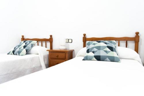 two twin beds in a bedroom with a night stand at Casa céntrica con vistas a la sierra in Hornachuelos