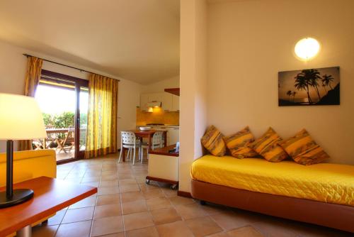 Cala Paradiso Residence في سان تيودورو: غرفة نوم بسرير اصفر ومطبخ