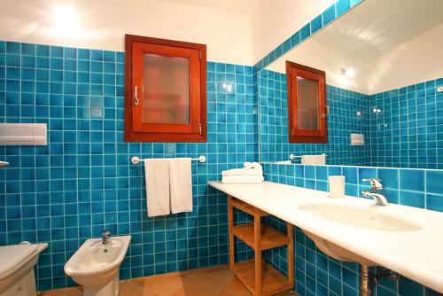uma casa de banho em azulejos azuis com 2 lavatórios e um WC em Cala Paradiso Residence em San Teodoro