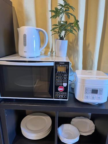 a microwave on a shelf with plates and a plant at 大阪旅・四葉　 in Osaka
