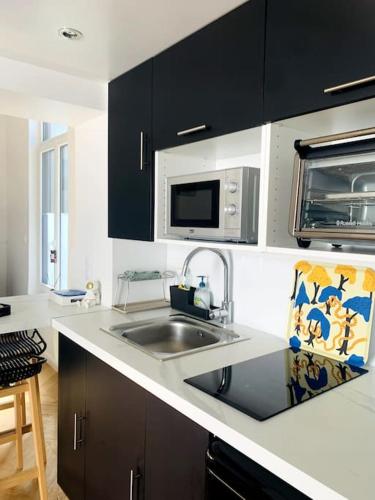 une cuisine avec un évier et un micro-ondes dans l'établissement L'escale Béthunoise - Maison duplex, hyper-centre, à Béthune