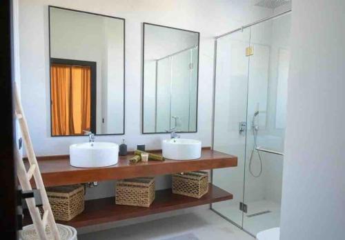 uma casa de banho com 2 lavatórios e uma cabina de duche em vidro. em Villa Alanaé avec piscine chauffée em Marrakech