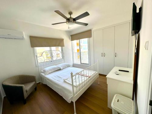 een slaapkamer met een bed en een plafondventilator bij Sea View Apt - 2 min walk to the Beach & 200 Mbit Highspeed internet in Larnaka