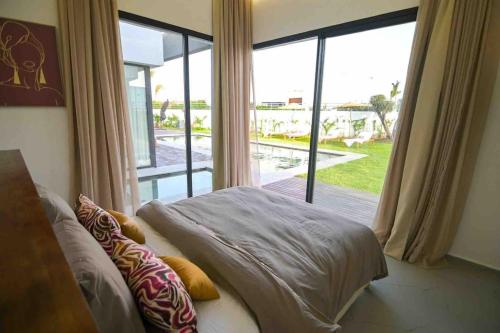 um quarto com uma cama e uma grande janela em Villa Alanaé avec piscine chauffée em Marrakech