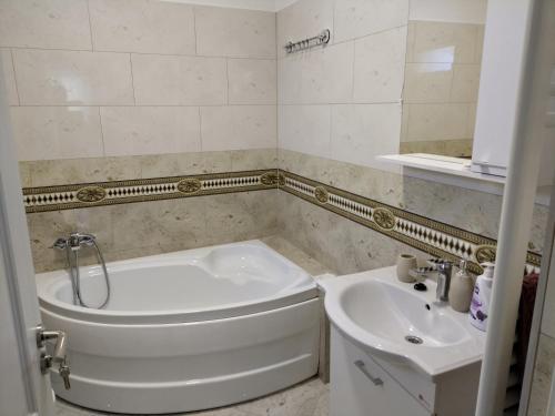 y baño con bañera blanca y lavamanos. en TSG apartament 2, en Valea lui Mihai