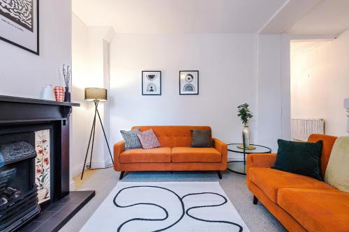 a living room with an orange couch and a fireplace at Modern 4 Bed Chester Townhouse with FREE Parking in Christleton