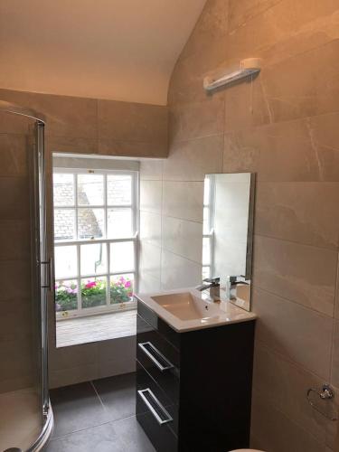 a bathroom with a sink and a mirror and a window at Perfect Apartment in ideal location in Ennistymon