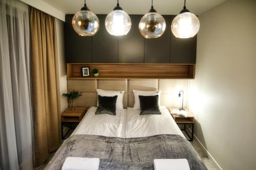 - une chambre avec un lit et trois lumières au-dessus dans l'établissement Apartamenty Laguna Beskidów - A95, à Zarzecze