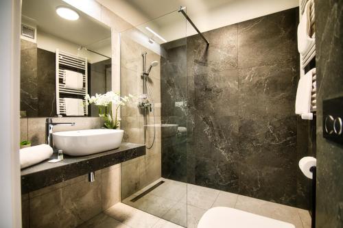 La salle de bains est pourvue d'un lavabo et d'une douche en verre. dans l'établissement Apartamenty Laguna Beskidów - A95, à Zarzecze