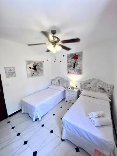 a bedroom with two beds and a ceiling fan at Hotelito Suecia in Granada