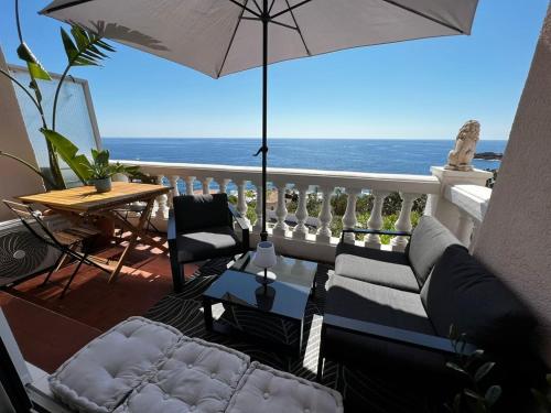 une terrasse avec un canapé, une table et un parasol dans l'établissement Trésor d’Anthéor, à Saint-Raphaël