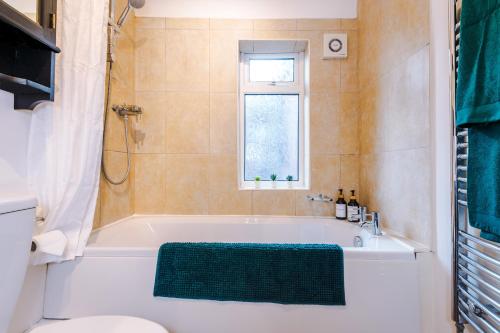 a bathroom with a tub and a toilet and a window at Modern 4 Bed Chester Townhouse with FREE Parking in Christleton