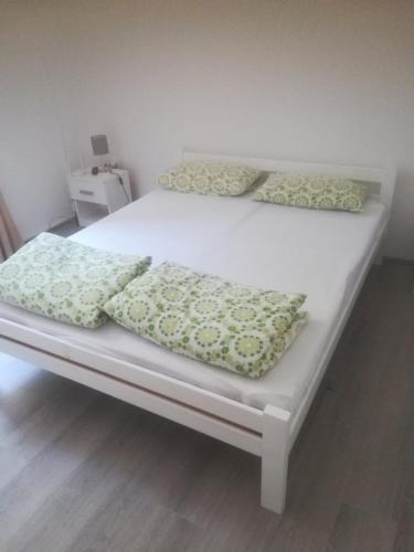 a bed with three pillows on top of it at Apartmani Pasuljevic in Veliko Gradište