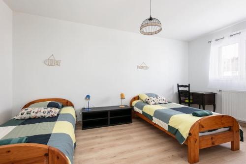 two beds in a bedroom with white walls and wooden floors at Maison neuve au centre-ville proche de l'aéroport in Guipavas