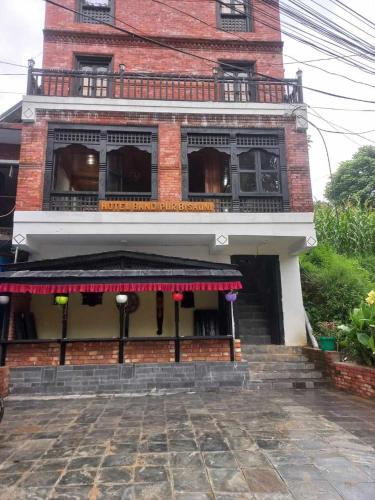 a brick building with a red awning on it at Hotel Bandipur Bisauni in Bandīpur