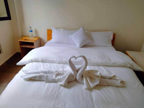 1 cama blanca con 2 toallas en forma de corazón en Hotel Bandipur Bisauni, en Bandipur