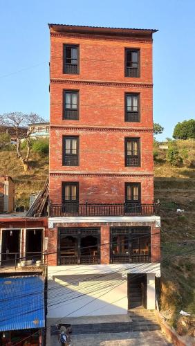 a red brick building with a balcony on a hill at Hotel Bandipur Bisauni in Bandipur