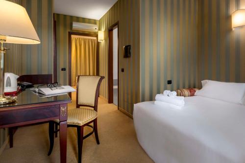 a hotel room with a bed and a desk and a desk at Best Western Cavalieri Della Corona in Cardano al Campo