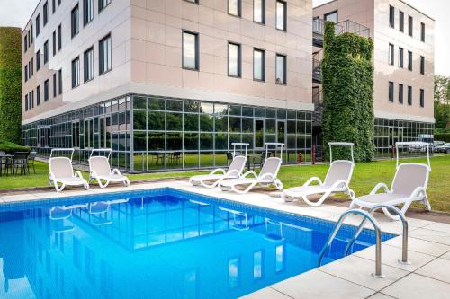 a swimming pool with chairs and a building at Best Western Cavalieri Della Corona in Cardano al Campo