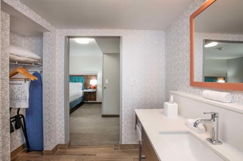 a bathroom with a sink and a mirror and a bedroom at Hampton Inn Dry Ridge in Dry Ridge