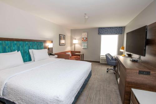 a hotel room with a bed and a flat screen tv at Hampton Inn Dry Ridge in Dry Ridge
