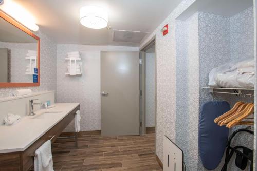 a bathroom with a sink and a door to a shower at Hampton Inn Dry Ridge in Dry Ridge