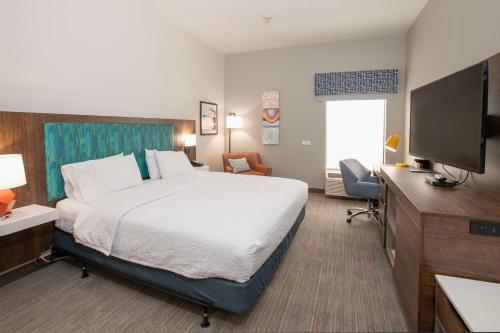 a hotel room with a bed and a flat screen tv at Hampton Inn Dry Ridge in Dry Ridge