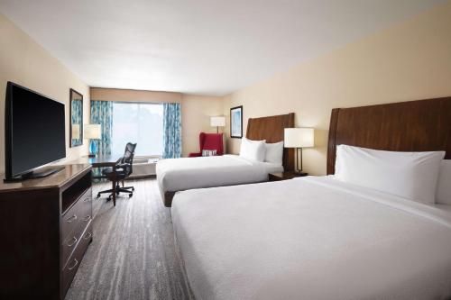 a hotel room with two beds and a flat screen tv at Hilton Garden Inn Houston/Bush Intercontinental Airport in Houston